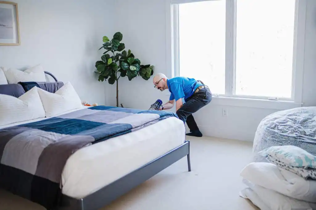 A Best Day Housecleaning cleaner making a bed during a cleaning visit.