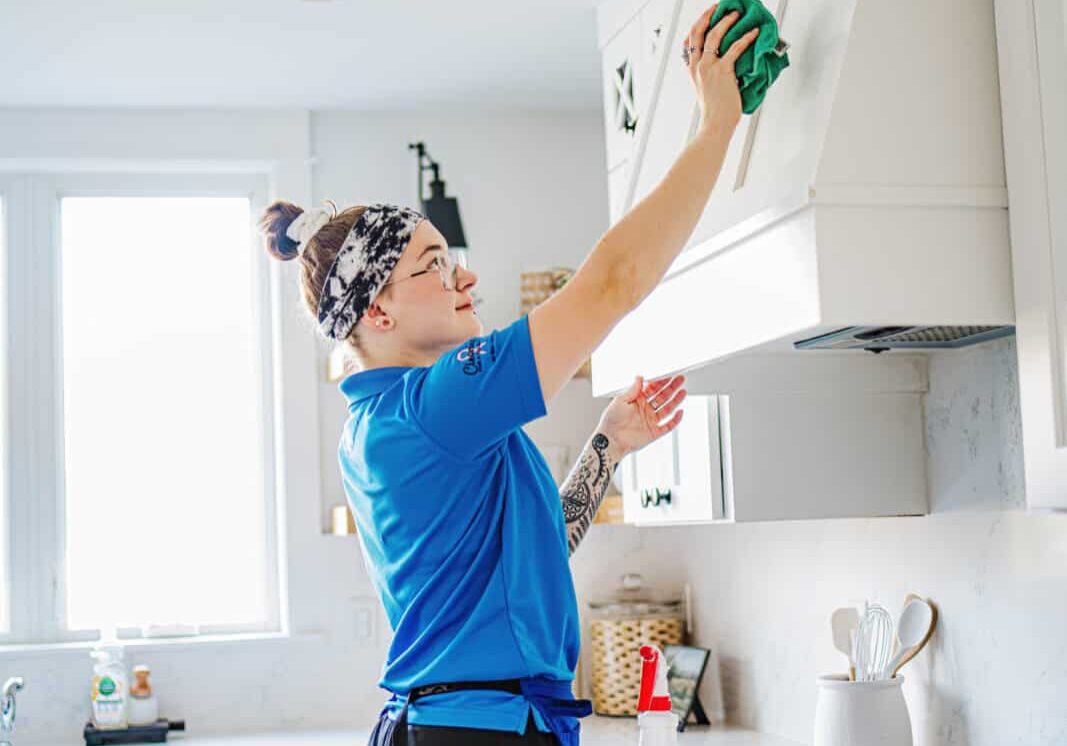 A Best Day Housecleaning cleaner wiping cabinets during a cleaning visit.