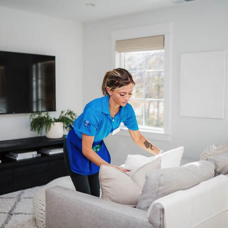 A Best Day Housecleaning cleaner fluffing pillows during a cleaning visit.