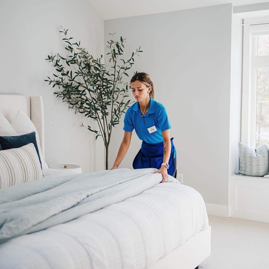 A Best Day Housecleaning cleaner making a bed during a cleaning visit.
