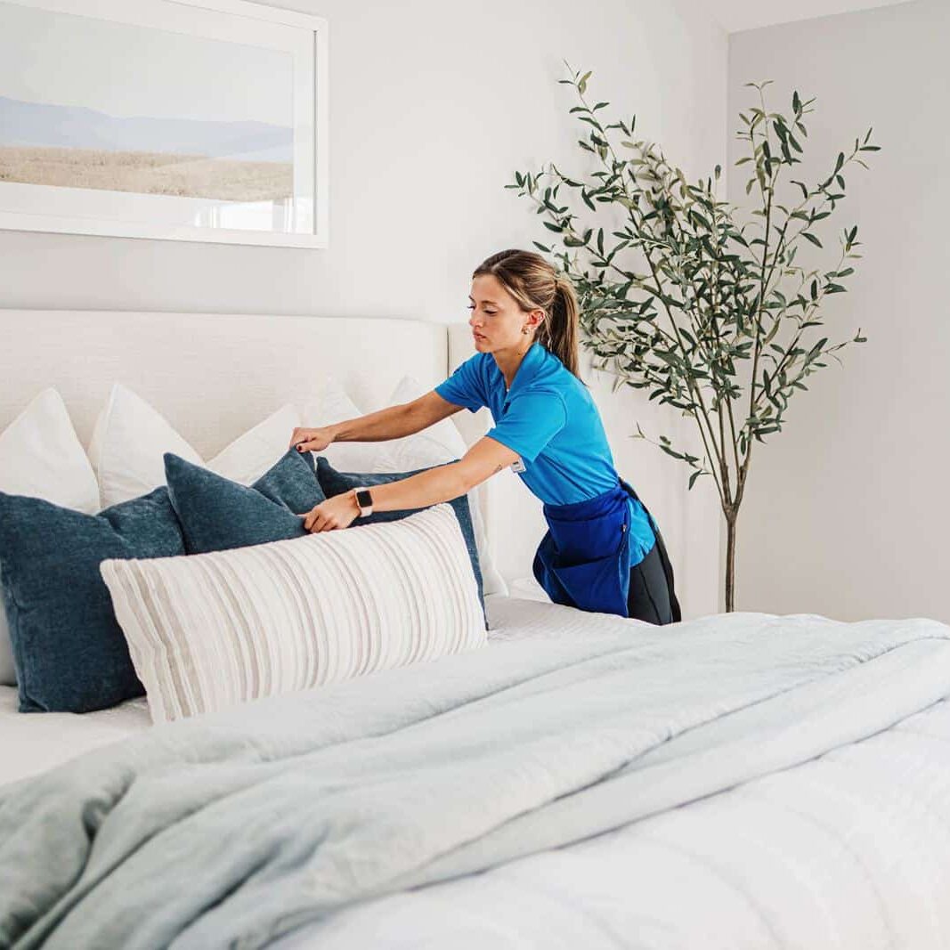 A Best Day Housecleaning cleaner making a bed during a cleaning visit.